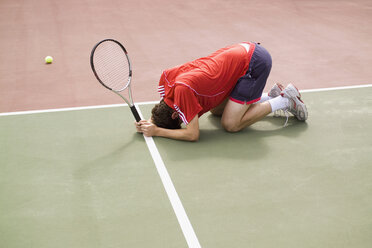 Ein Tennisspieler, der in der Niederlage auf dem Boden hockt - FSIF02416