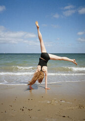 A woman doing a cartwheel on a beach - FSIF02425
