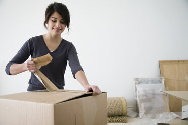 Teenage girl unpacking cardboard boxes - FSIF02431