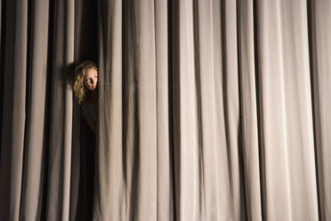 Eine Frau späht durch einen Bühnenvorhang - FSIF02440
