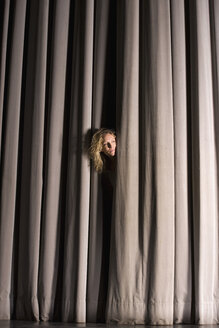 Eine Frau späht durch einen Bühnenvorhang - FSIF02446