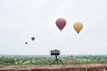 Myanmar, smartphone taking a time lapse of many hot air balloons flying over Bagan - IGGF00432