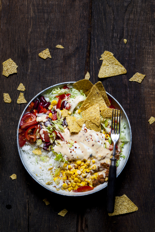 Taco salad bowl with rice, corn, chili con carne, kidney beans, iceberg lettuce, sour cream, nacho chips, tomatoes stock photo