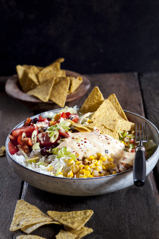 Taco salad bowl with rice, corn, chili con carne, kidney beans, iceberg lettuce, sour cream, nacho chips, tomatoes stock photo