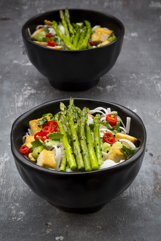 Schüssel mit veganem Pad Thai mit Mini-Grünspargel und Tofu, Chili, Frühlingszwiebeln, Erdnuss und Koriander, lizenzfreies Stockfoto