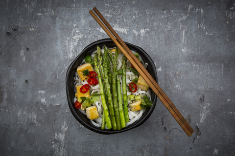 Bowl of vegan Pad Thai with mini green asparagus and tofu, chili, spring onion, peanut and coriander stock photo