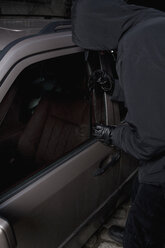 Ein vermummter Mann bricht in ein Auto ein - FSIF02478