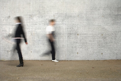 Two people walking past a wall - FSIF02511
