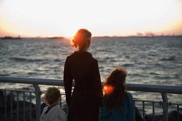 Eine Mutter und zwei Kinder schauen auf das Meer hinaus - FSIF02533
