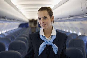 A flight attendant standing in the cabin of a plane - FSIF02583