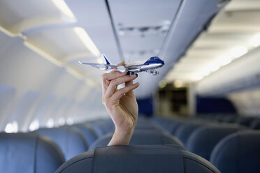 A hand holding a toy airplane above an airplane seat - FSIF02597