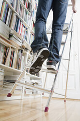 A man's legs climbing up a ladder that's about to tip over - FSIF02608