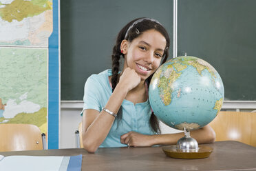 Portrait of a schoolgirl sitting near a globe - FSIF02631