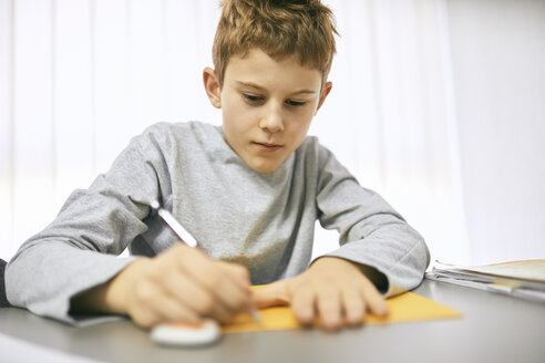 Schoolboy writing on desk in class - ZEDF01188