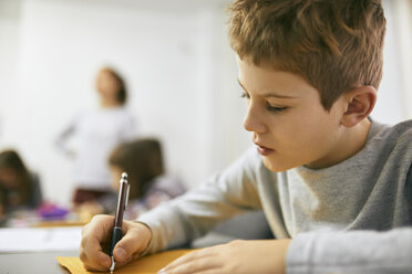 Schoolboy writing on desk in class - ZEDF01191