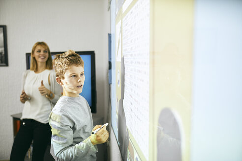 Schüler im Unterricht am interaktiven Whiteboard mit Lehrer im Hintergrund - ZEDF01198