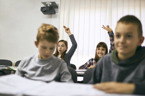 Schüler in der Klasse mit zwei Mädchen, die ihre Hände heben - ZEDF01204