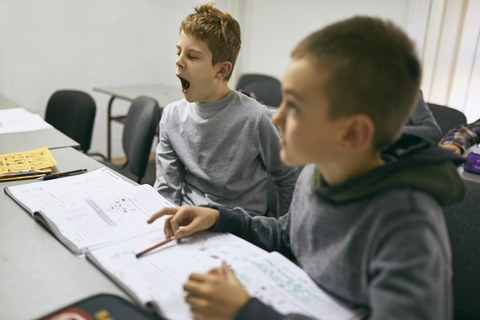 Schüler lernen im Unterricht mit gähnendem Jungen, lizenzfreies Stockfoto