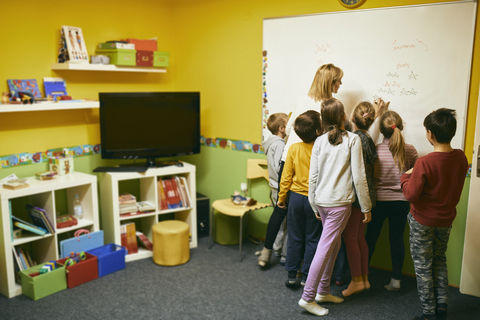 Teacher with students writing on whiteboard stock photo