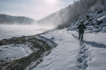 Russland, Gebiet Amur, Mann spaziert am Ufer des Flusses Bureya in schneebedeckter Natur - VPIF00311