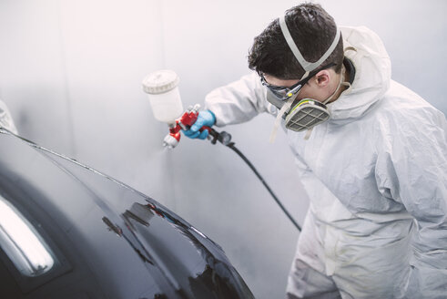 Auto painter painting a car inside a paint booth - RAEF01973