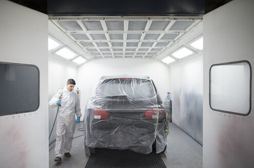 Auto painter painting a car inside a paint booth - RAEF01981