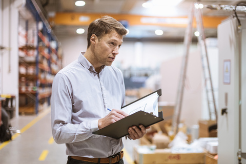 Businessman in factory holding folder stock photo