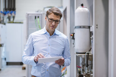 Portrait of businessman in factory holding tablet - DIGF03408