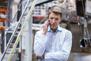 Businessman on cell phone in factory - DIGF03409