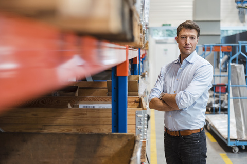 Porträt eines selbstbewussten Geschäftsmannes in einem Fabriklagerraum, lizenzfreies Stockfoto