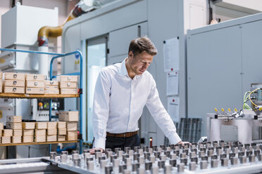 Businessman in factory looking at machine - DIGF03421