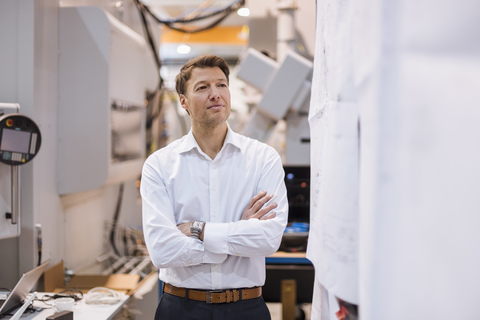 Confident businessman in factory looking around stock photo