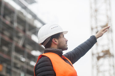 Mann mit Sicherheitsweste und Schutzhelm auf einer Baustelle - SGF02191