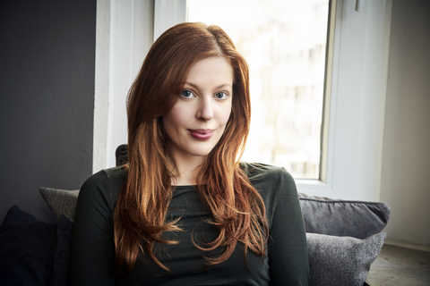 Portrait of redheaded woman in front of window at home stock photo