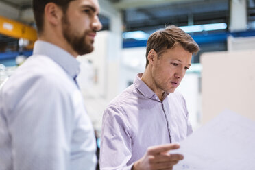 Two men in factory looking at plan - DIGF03429