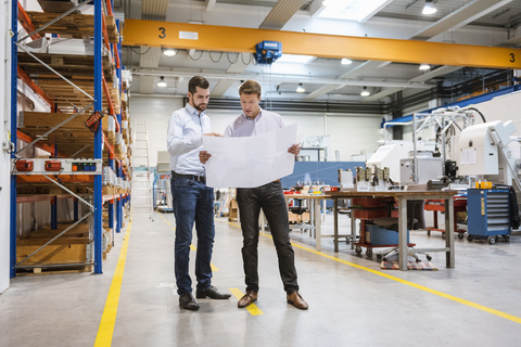 Two men in factory looking at plan stock photo