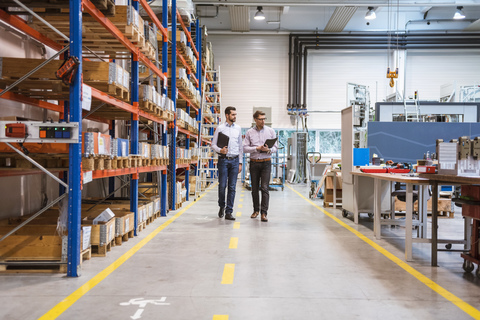 Zwei Männer gehen in einer Fabrik, lizenzfreies Stockfoto