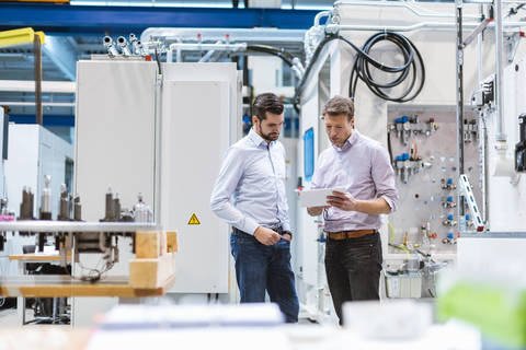 Two men in factory looking at tablet stock photo