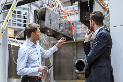 Two businessmen discussing in factory stock photo