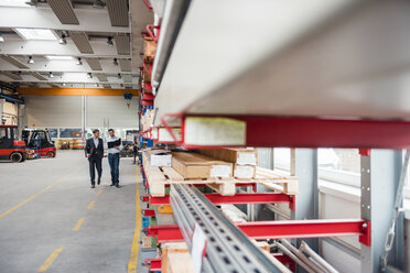 Two men walking and talking in factory shop floor - DIGF03449