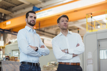 Two confident businessmen in factory looking around - DIGF03454