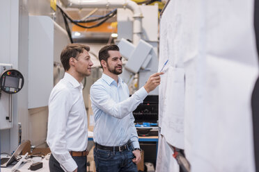 Two men in factory looking at plan - DIGF03455