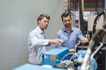 Two men discussing at machine in factory - DIGF03457