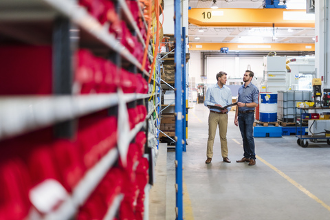 Two men with folder in factory storeroom stock photo