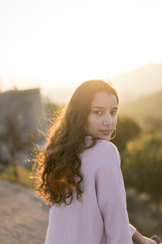 Portrait of young woman with long curly hair at sunset stock photo