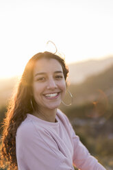 Porträt einer lachenden jungen Frau mit langen Haaren bei Sonnenuntergang - AFVF00122