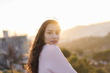 Portrait of young woman with long curly hair at evening twilight - AFVF00123