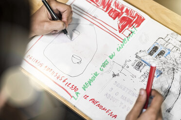 Artist sitting in cafe, drawing into his notebook - SBOF01384