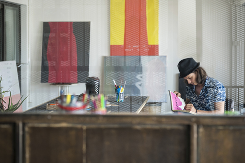 Künstler bei der Arbeit, Zeichnung in einem Notizbuch in seinem Loft-Atelier, lizenzfreies Stockfoto