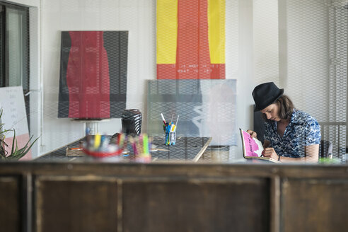 Künstler bei der Arbeit, Zeichnung in einem Notizbuch in seinem Loft-Atelier - SBOF01400